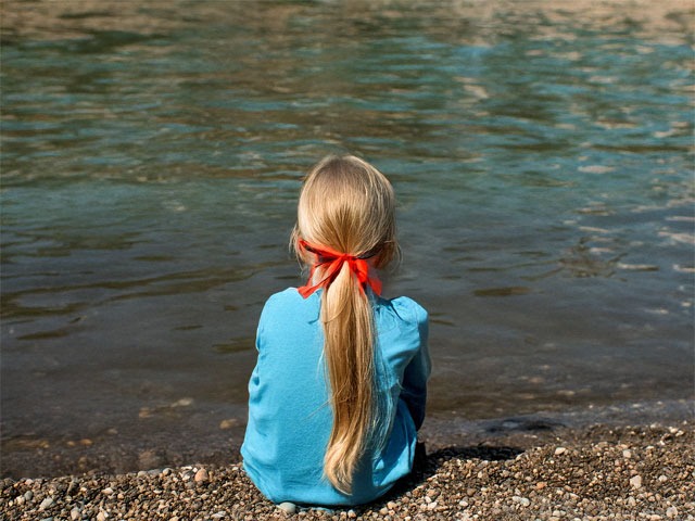 暗い海岸で金髪の赤いリボンのポニーテールで青い服を着た女の子がおじいちゃんに呼び掛けている（生成画像）